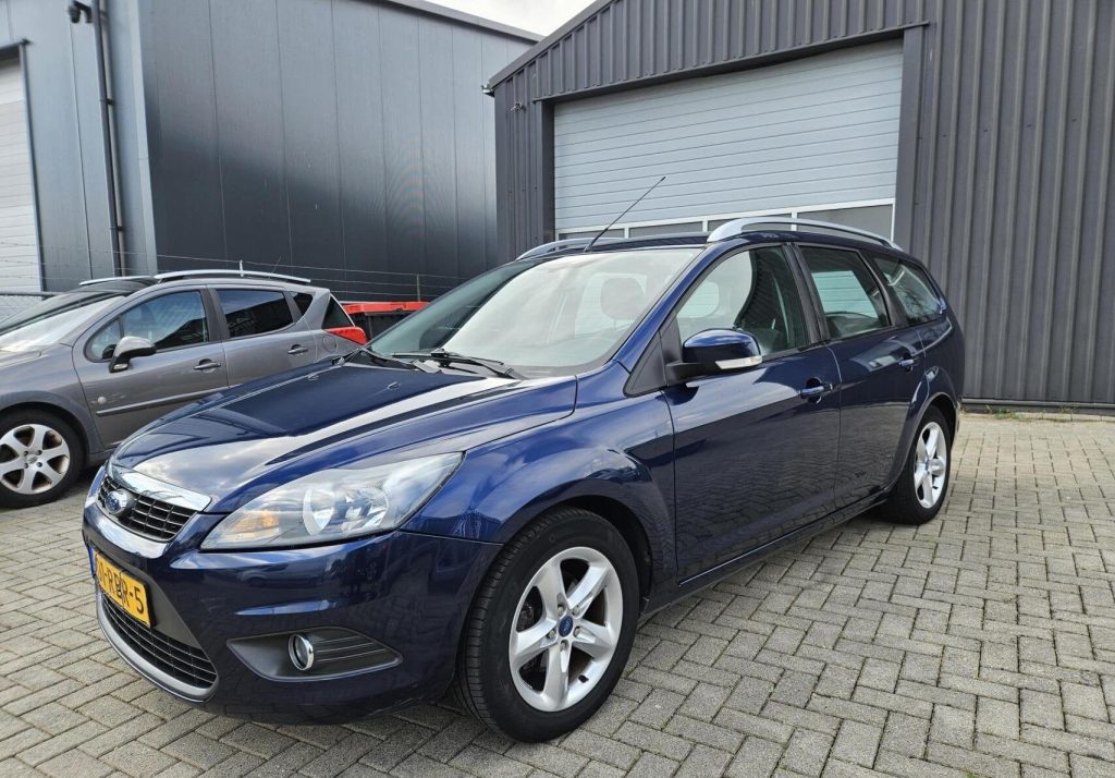 Een Ford Focus Wagon op het terrein van Autobedrijf Adonis, voor de antracieten hal met grijze roldeur