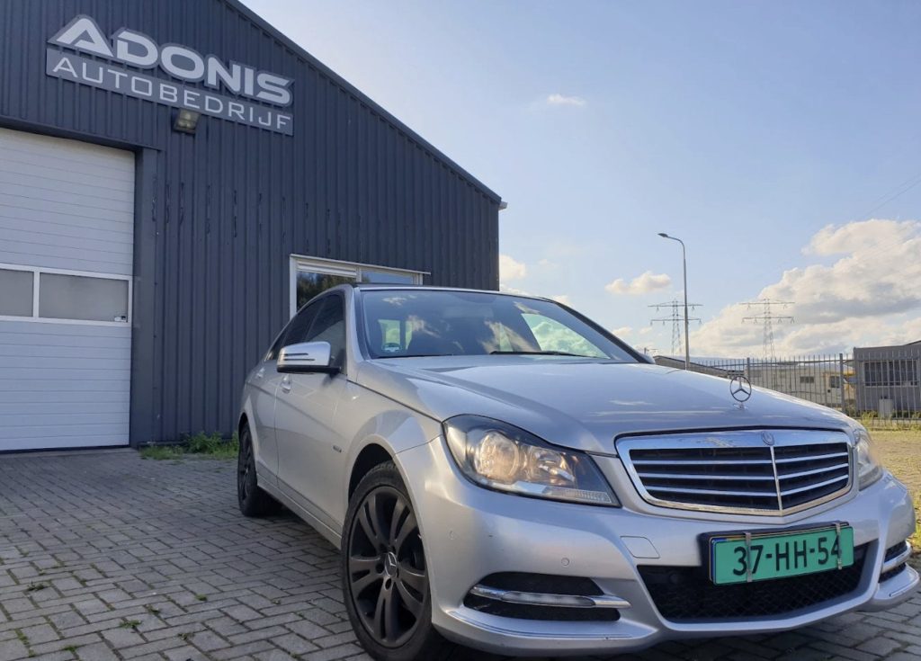 Het pand van Autobedrijf Adonis aan de Adonisweg in Leeuwarden, met ADONIS AUTOBEDRIJF op de gevel en een zilveren Mercedes ervoor